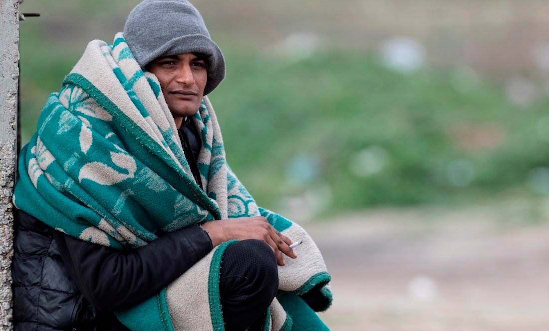 Un migrante pakistaní, cubierto con una manta, descansa cerca de la frontera entre Turquía y Grecia. (Foto: EFE)