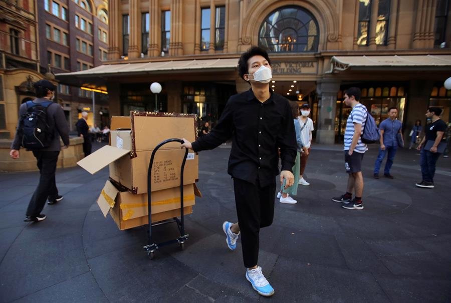 Un trabajador con la mascarilla puesta mueve cajas en Sidney, Australia. (Foto: EFE)