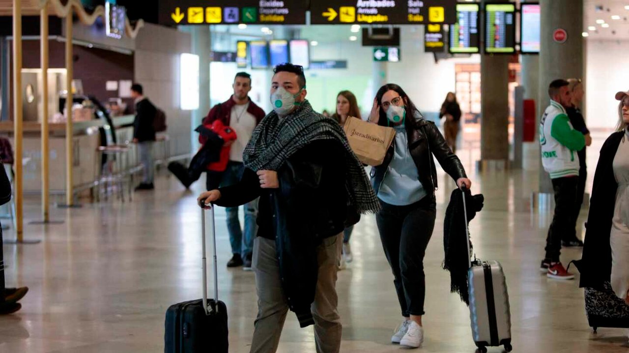 Varios pasajeros en un aeropuerto con mascarilla (EFE).
