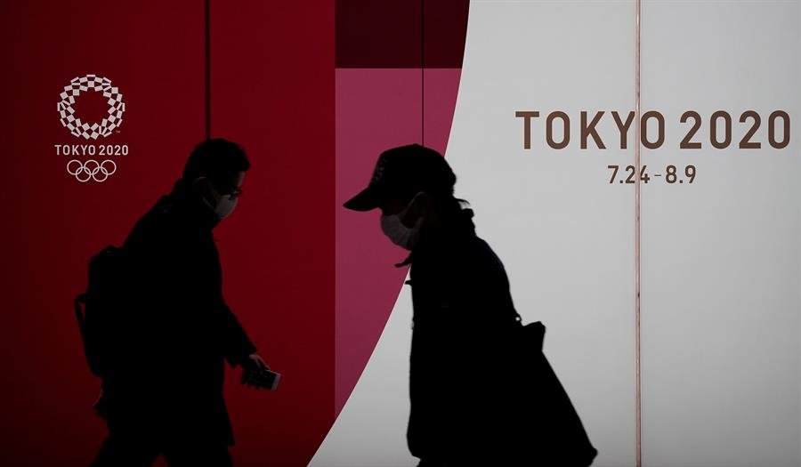 Dos transeúntes pasan por delante del logo de Tokyo 2020. (Foto: EFE)
