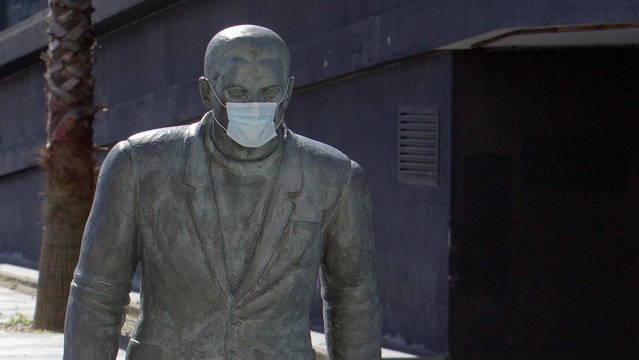 Escultura dedicada a la emigración, en el puerto de Vigo, con máscara alusiva a la pandemia.