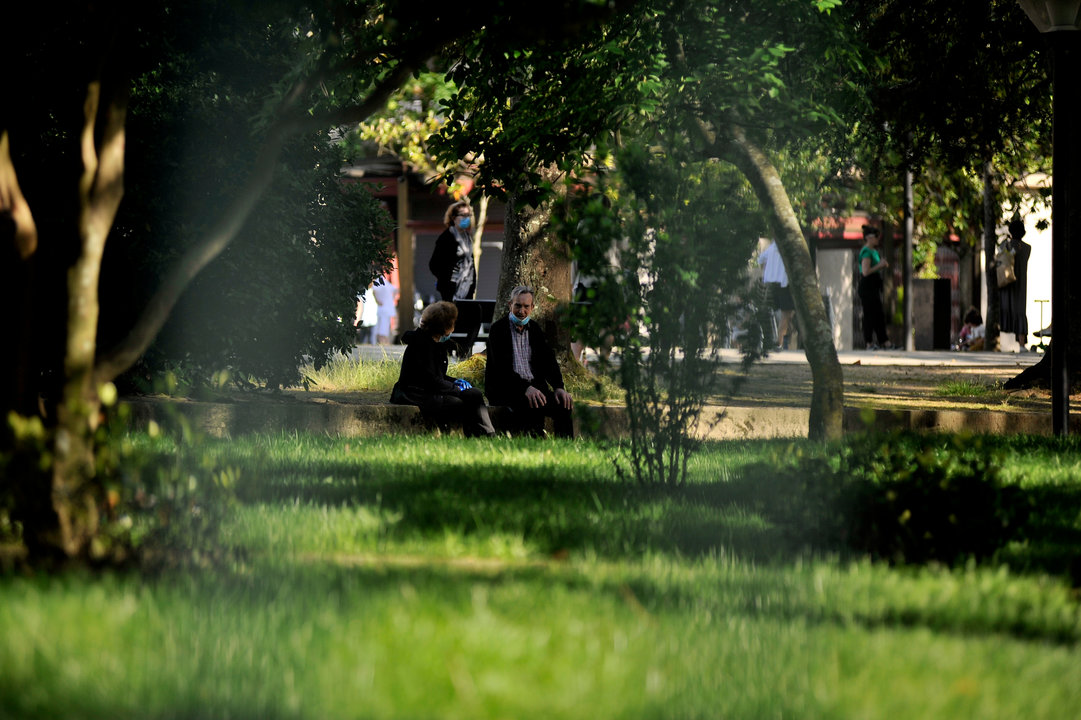 Dos personas mayores conversan en el jardín del Posío, en la ciudad. // Martiño Pinal