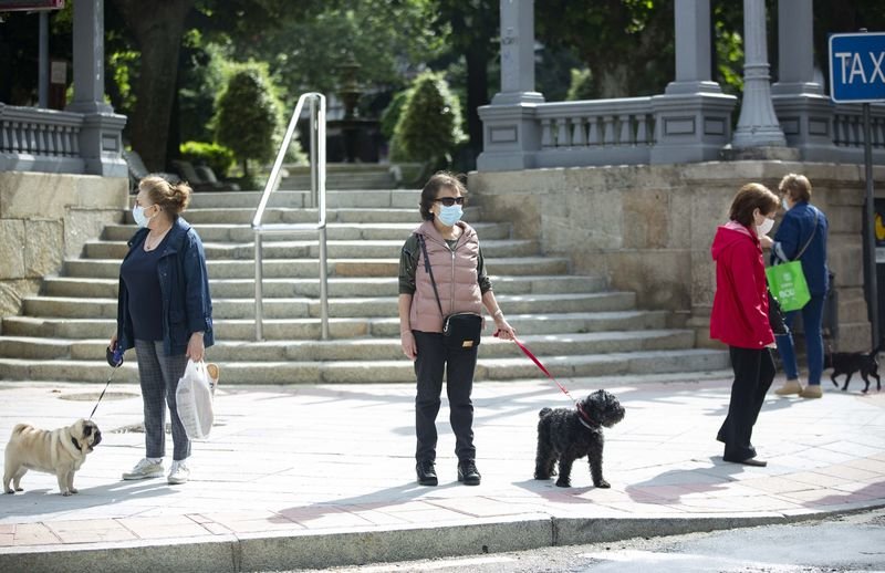 En el plano más cercano, dos mujeres observan a diferentes puntos de la ciudad mientras están detenidas en las escaleras de San Lázaro junto a sus perros (XESÚS FARIÑAS).