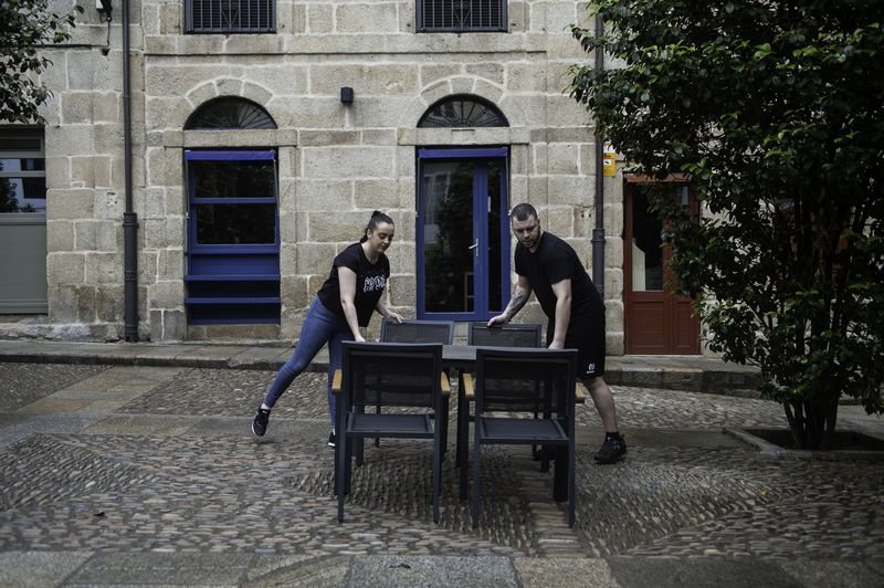 Rocío Mariño y José Luis Fernández preparan una de las mesas que instalarán desde mañana lunes en su local, el Tapa Negra (MARTIÑO PINAL).