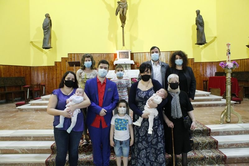 Álex -izquierda- en brazos de su tía y Xosé -derecha- en los de su madre, posan con la familia en su bautizo.