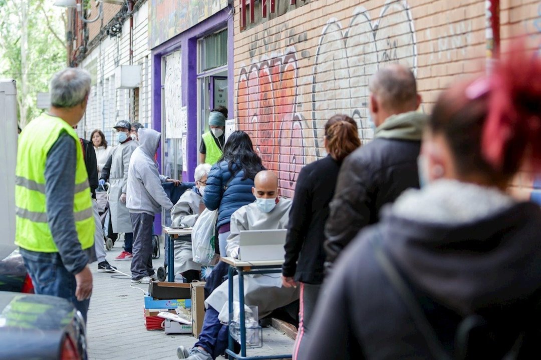 Varias personas aguardan su turno para entrar al economato de Cáritas en el distrito madrileño de Tetuán.