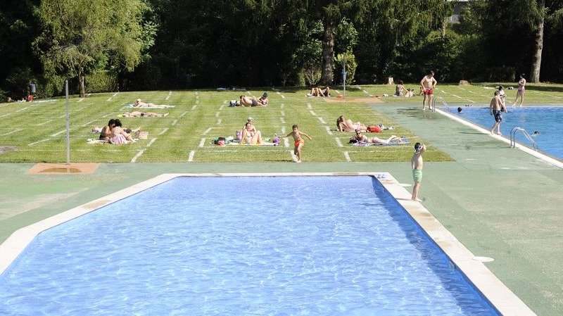 Primeros usuarios de las piscinas municipales de Carballiño, que abrieron ayer con medidas de seguridad como las parcelas en el césped.