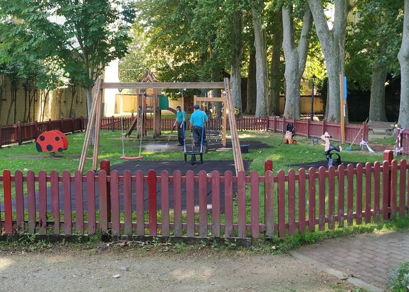 Dos operarios municipales limpian el parque infantil del jardín de la Casa Grande, en Viloira.