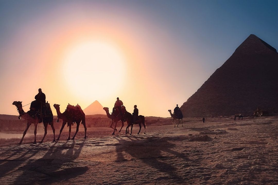 Jinetes en camello junto a unas pirámides, en Egipto. (Foto: Unpslash)