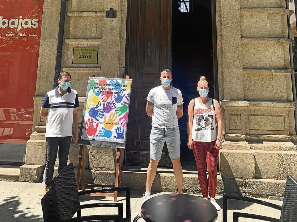 Voluntarios de Atox posan con el cartel homenaje del evento en la puerta de su sede de la Rúa do Paseo.