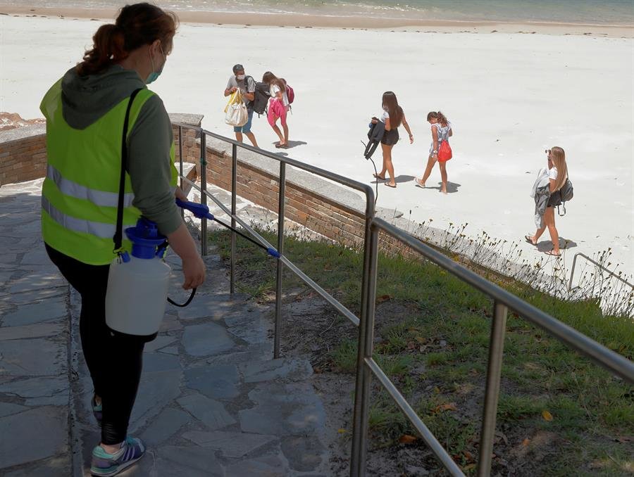 Una mujer desinfecta una de las barandillas de la playa de O Vicedo, en Lugo, este martes. En la Mariña de Lugo se mantiene el confinamiento de cinco días prorrogables por un brote de coronavirus con más de un centenar de infectados. EFE/Eliseo Trigo