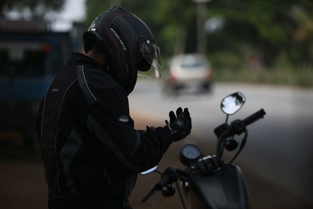 Un conductor se ajusta los guantes antes de subir a su moto. (Foto: Unsplash)