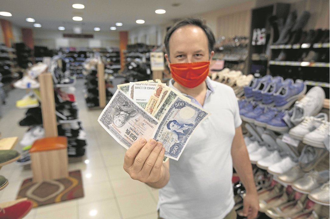 Javier Veloso muestra diversos billetes de peseta en su establecimiento de calzado de Lamas Carvajal.. // X. Fariñas