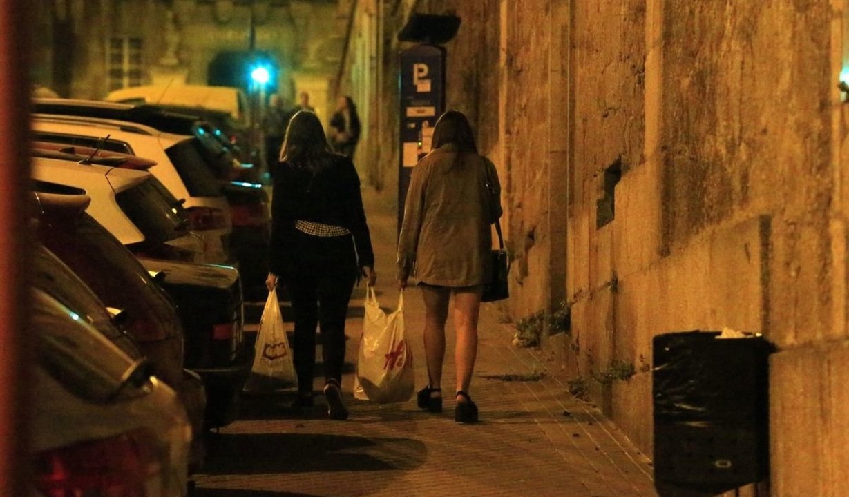 Dos jóvenes cargan una bolsa por las calles de Ourense.