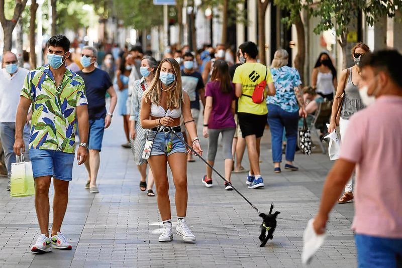 Un grupo de personas pasea por la calle con mascarillas.