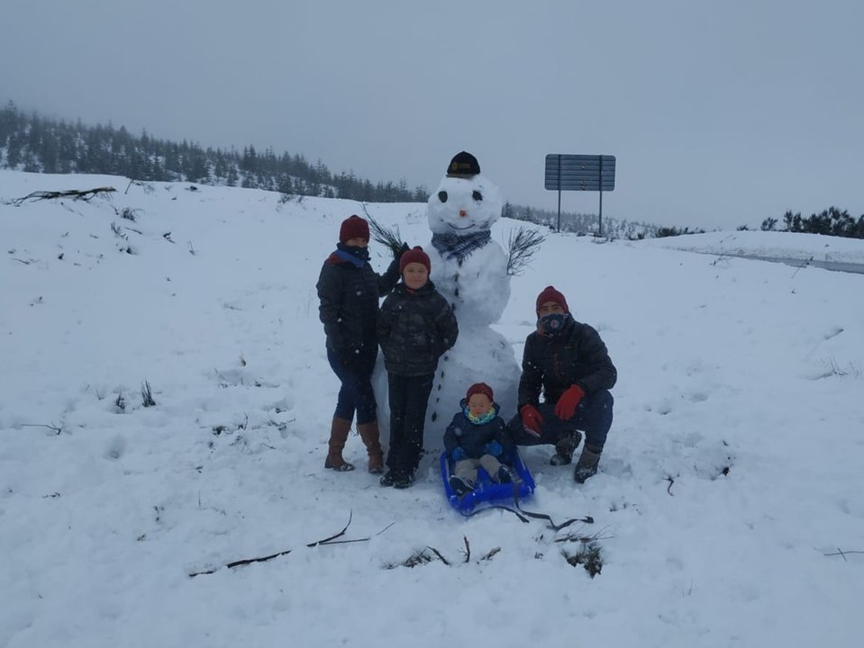 Una familia posa junto al muñeco de nieve que ha construido, este domingo. (Foto: José Paz)