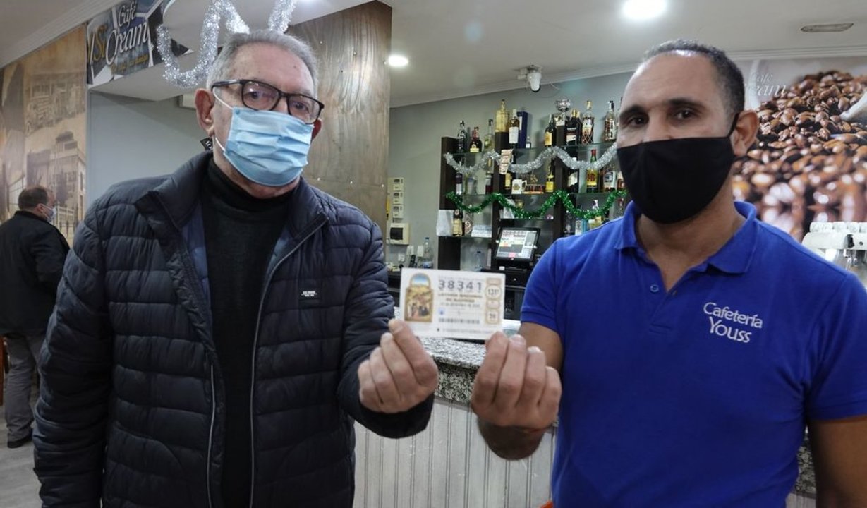 Jaime Lorenzo (izquierda) muestra el décimo premiado que había extraviado y que le entregó Youssef Abriga, propietario de Cafetería Youss.