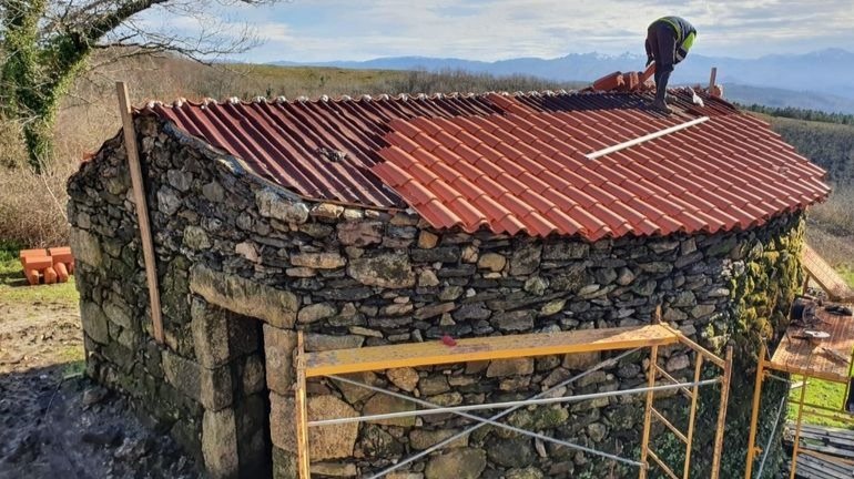 Uno de los operarios trabaja en la reforma del tejado del horno recuperado en Lobeira.