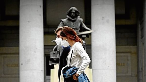 Una pareja pasea de la mano por delante de una estatua.