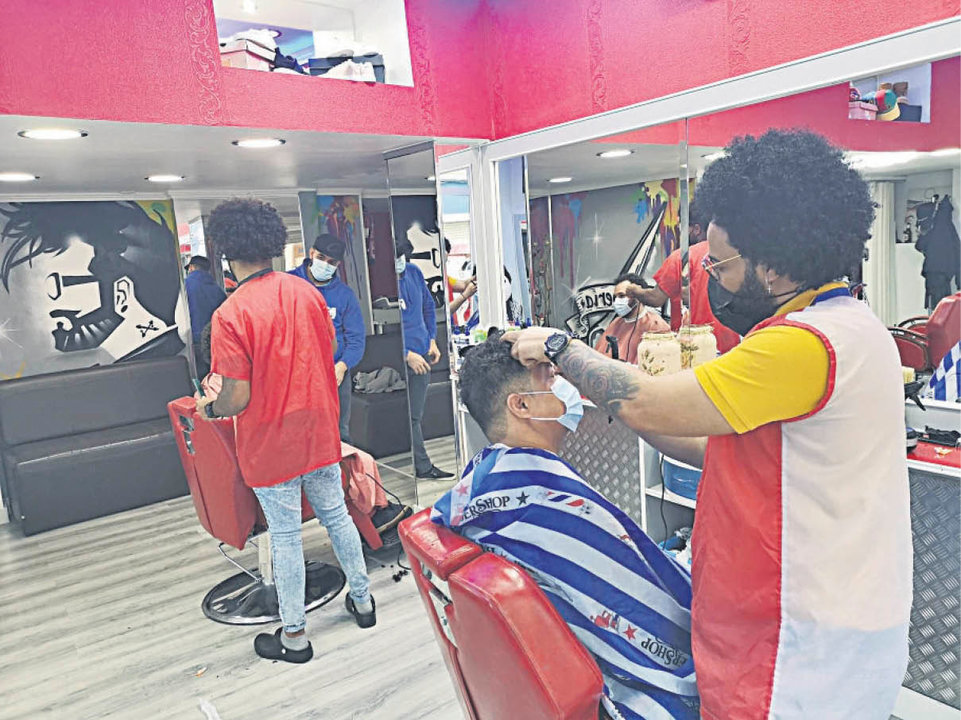 Osvaldo Zabalea y un trabajador peinando a sus clientes en su peluquería de Jesús Soria.