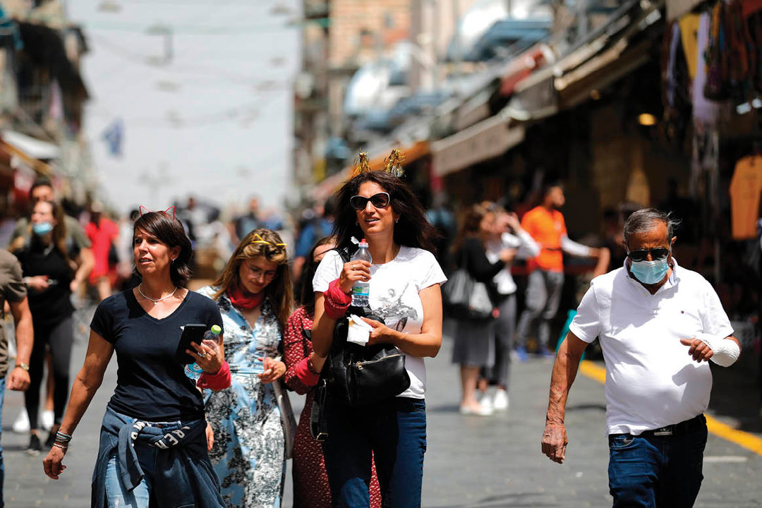 Tres mujeres caminan, sin mascarilla, por Jerusalén.