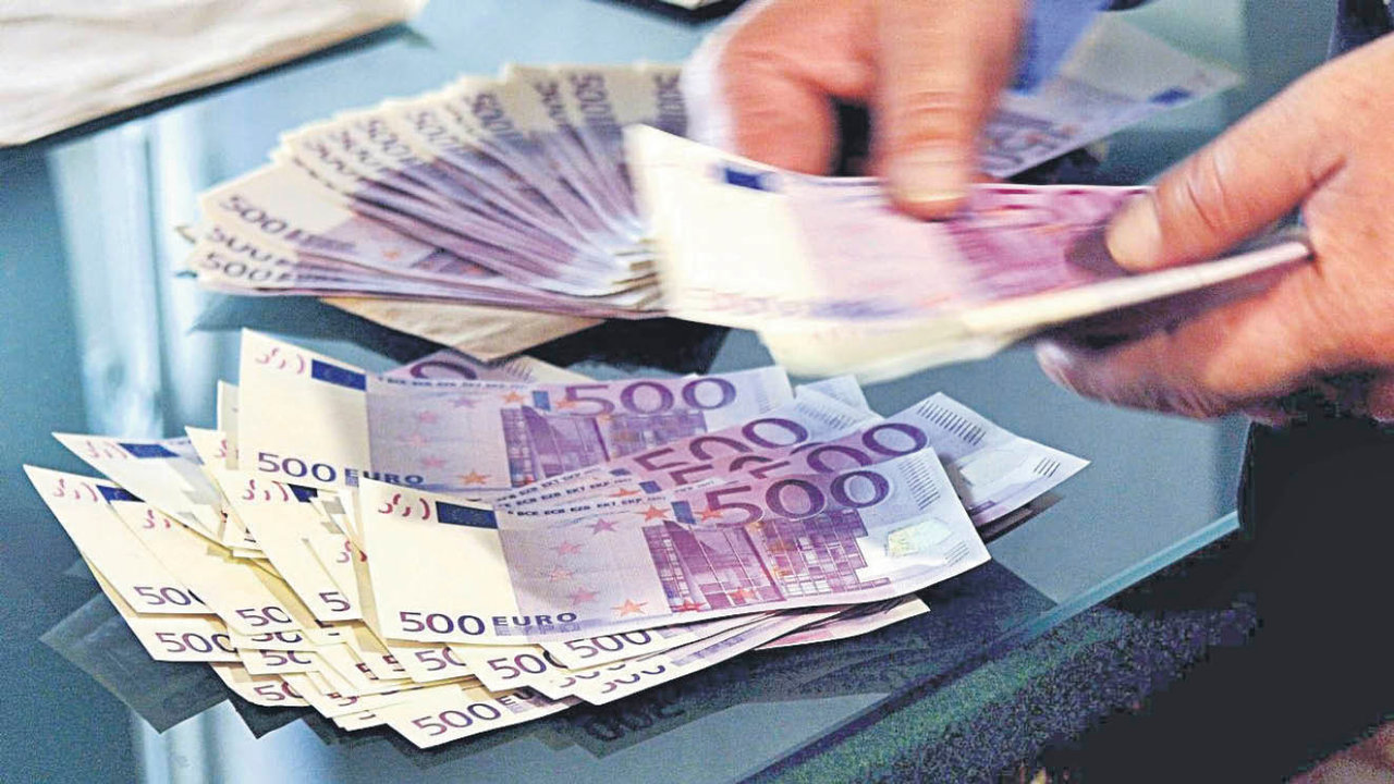 Una persona cuenta billetes de 500 euros sobre una mesa.