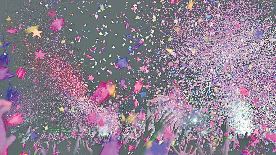 Jóvenes lanzando papelitos de colores al aire durante una fiesta.