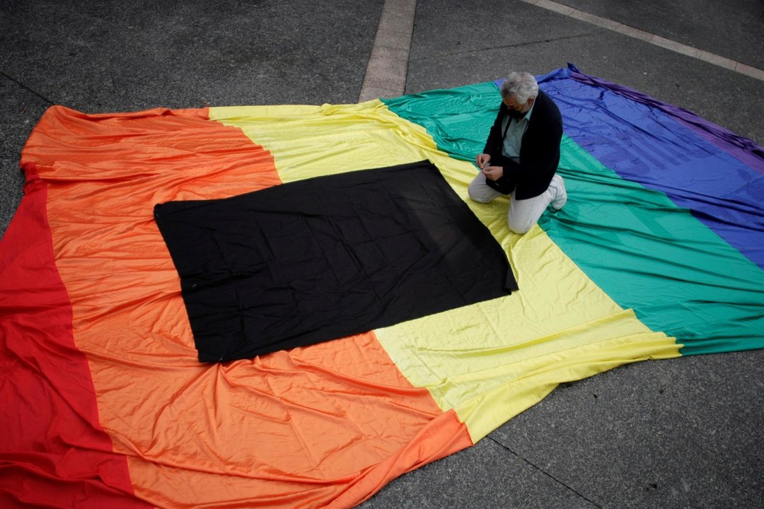 Un hombre coloca un crespón negro en una bandera arcoíris durante la manifestación contra la homofobia en A Coruña