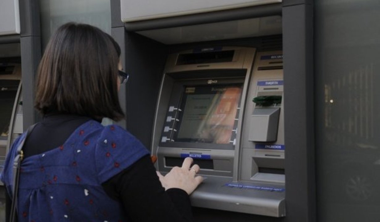  Una mujer trata de sacar dinero en el cajero automático de una sucursal bancaria. 