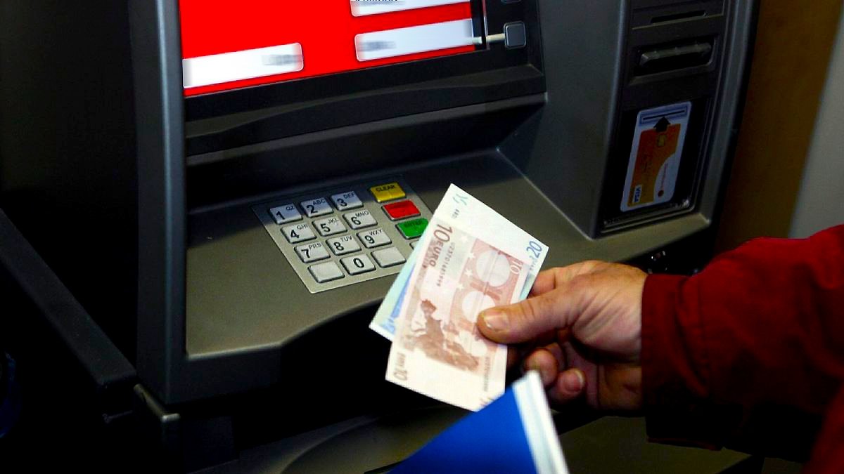  Un hombre retira dinero en efectivo en el cajero automático de una sucursal bancaria. 