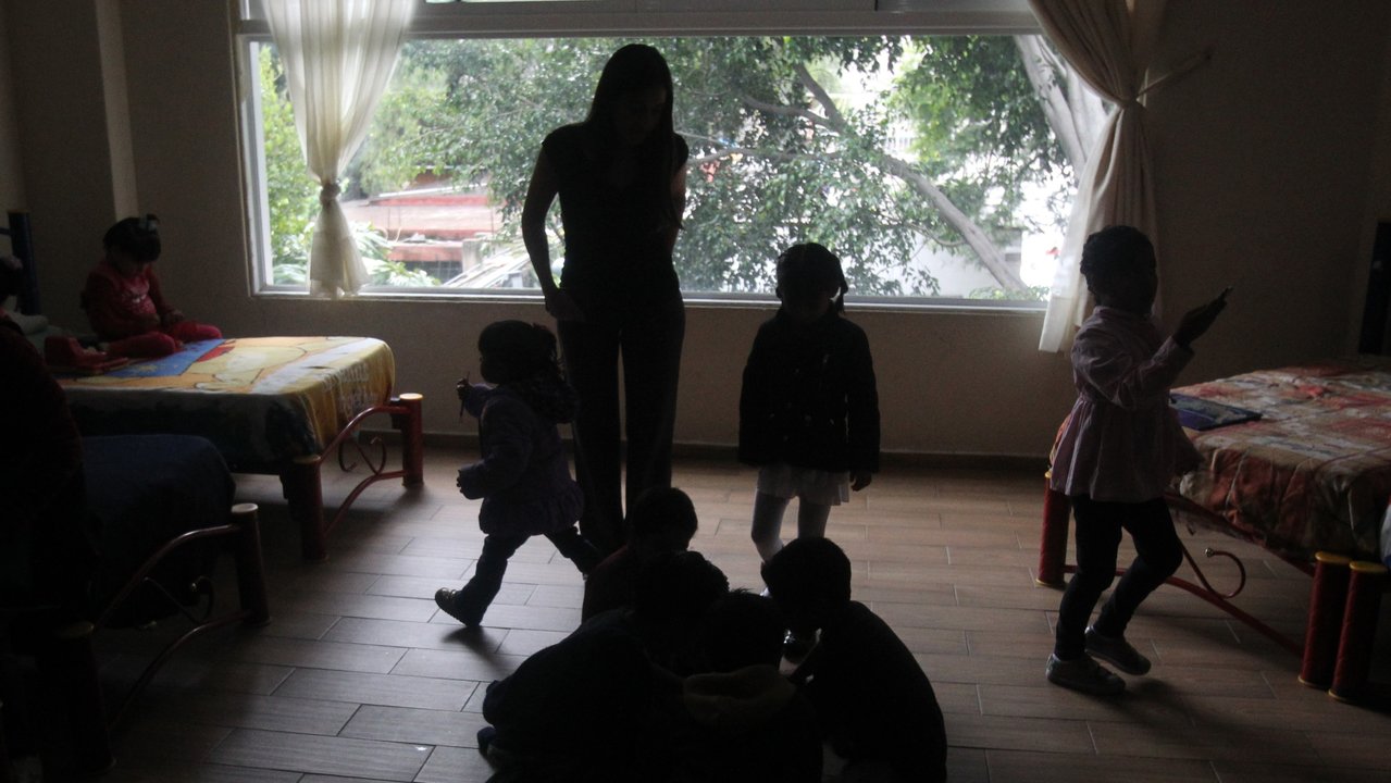  Un grupo de niños juega en un campamento ante la supervisión de una cuidadora. 