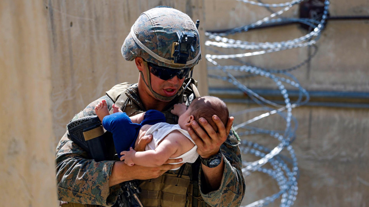 Un militar de Estados Unidos, consuela a un bebé en el aeropuerto de Kabul. EFE