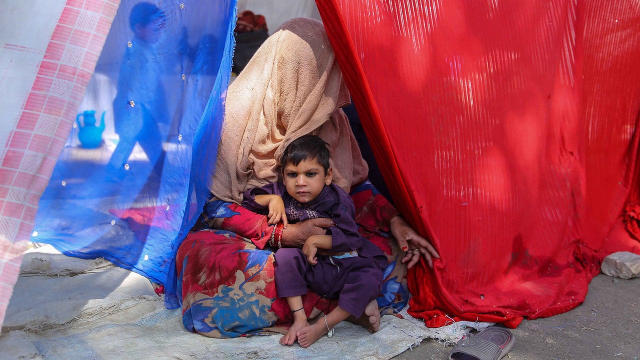  Un niño con su madre, totalmente tapada, en un campamento de refugiados internos en Kabul. 