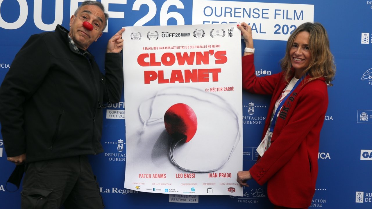 Héctor Carré, izquierda, posa junto al cartel de su documental, Clown's Planet