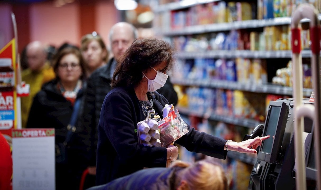 <p> Una mujer consulta precios al realizar sus compras en un supermercado. </p>