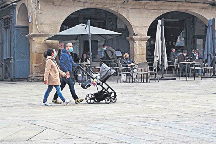 Una joven pareja pasea con un carrito de bebé por el centro de la ciudad (MARTIÑO PINAL).