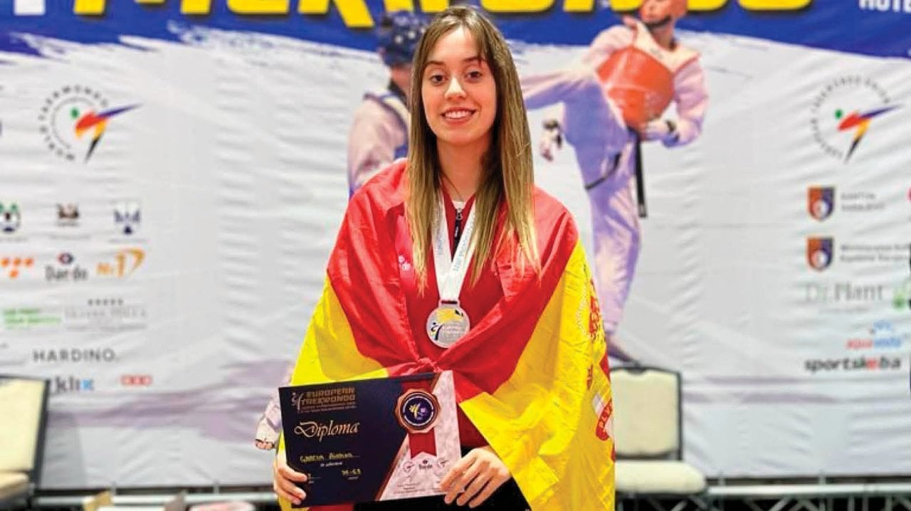 La taekwondista ourensana Ainoha García, envuelta en la bandera española, con la medalla continental y el trofeo