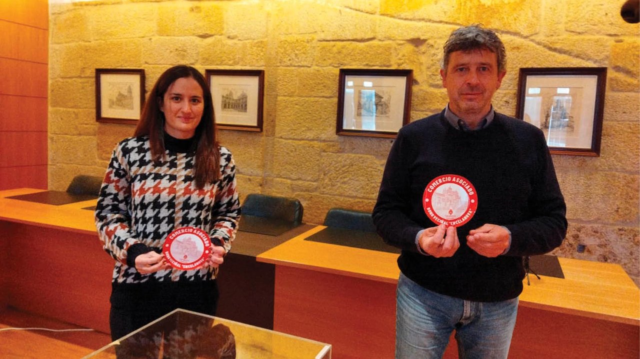 Sandra Feijóo y  Antonio Puga con el distintivo que identificará los comercios participantes.