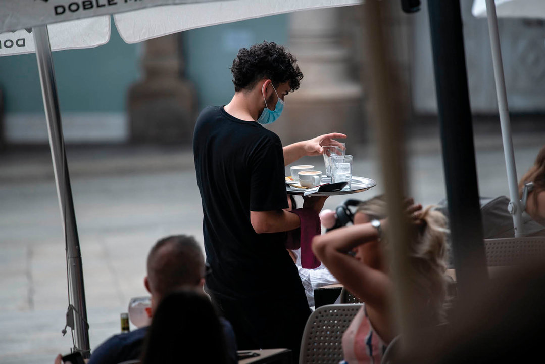 Un camarero, sirviendo una mesa en una terraza.