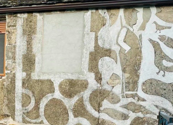 Un esgrafiado de un cazador rodeado de animales, en la fachada de una casa de O Bolo.