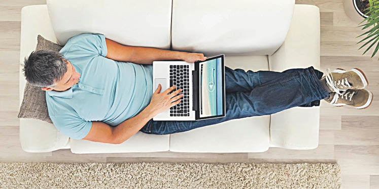 Un hombre sentado en el sofá con el ordenador en mano.