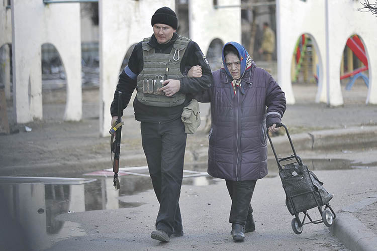 Un policía ucraniano ayuda a una mujer mayor a dirigirse a un lugar seguro en Kiev.