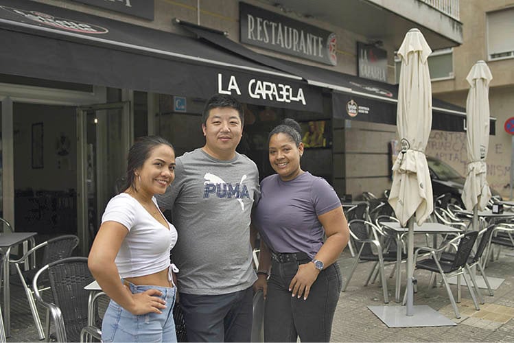 Juliana Morales, Wuan Pu y Yomaire González delante del Restaurante Cafetería La Carabela, en A Valenzá. (Xesús Fariñas)