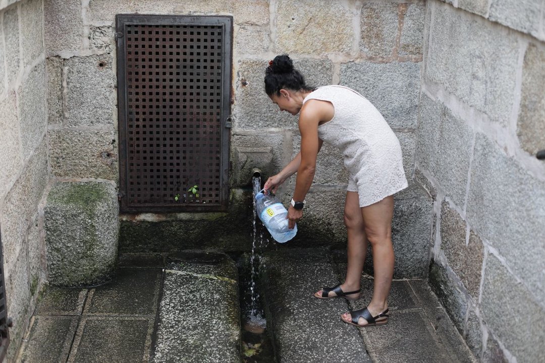 Una mujer llena una garrafa de agua, ayer, en Ribadavia. JOSÉ PAZ