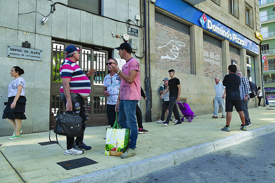 Usuarios del comedor social de Cáritas de la ciudad, frente a la entrada del local. (MARTIÑO PINAL)