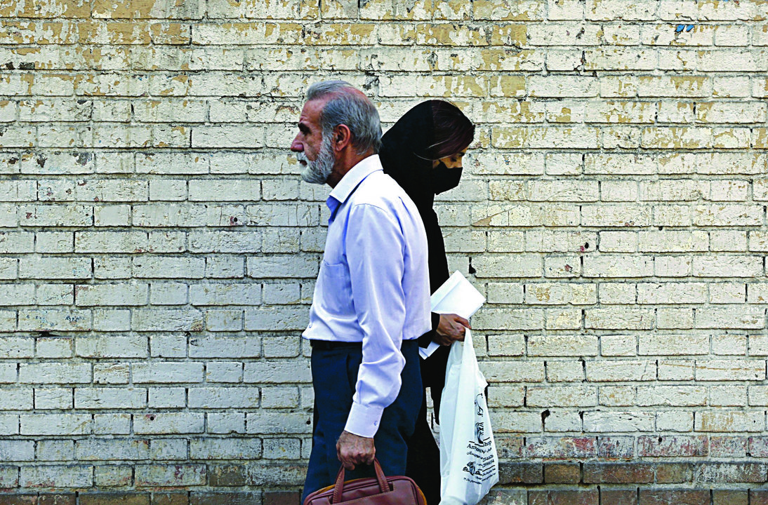 Una mujer y un hombre se cruzan en las calles de Teherán. (ABEDIN TAHERKENAREH)