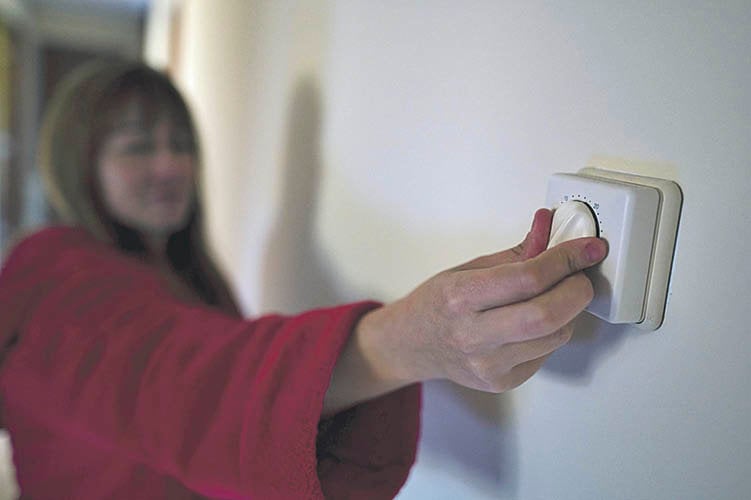 Una mujer regula el termostato de la calefacción en su vivienda.