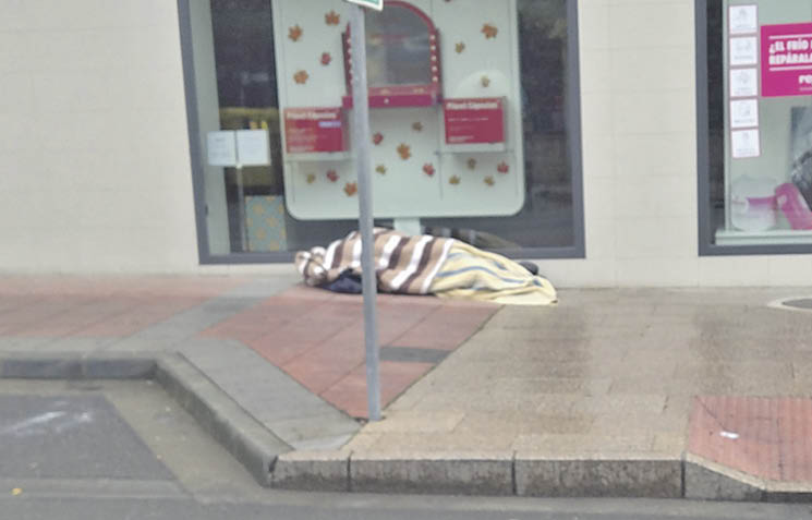 Un transeúnte durmiendo en una calle de O Barco.