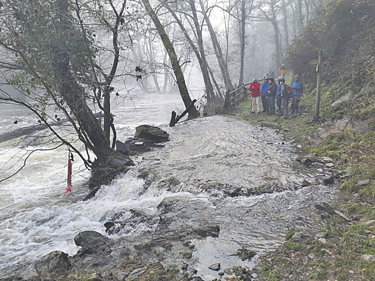 El desbordado río Arnoia de estas pluviosidades impide a los senderistas continuar con la ruta de senderismo.