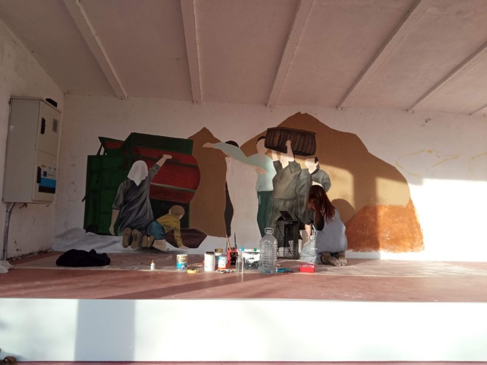 Ivette Bordera, a la derecha, de rodillas, pintando el mural de Zarracós que se inaugura este sábado. (L.F.)